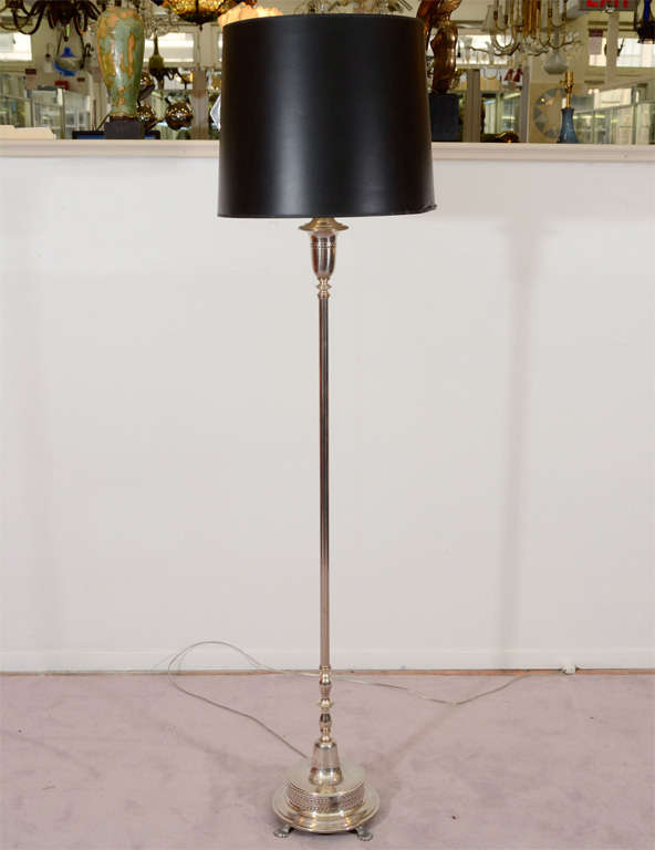 A vintage floor lamp in silver plate with a footed base and perforated detailing