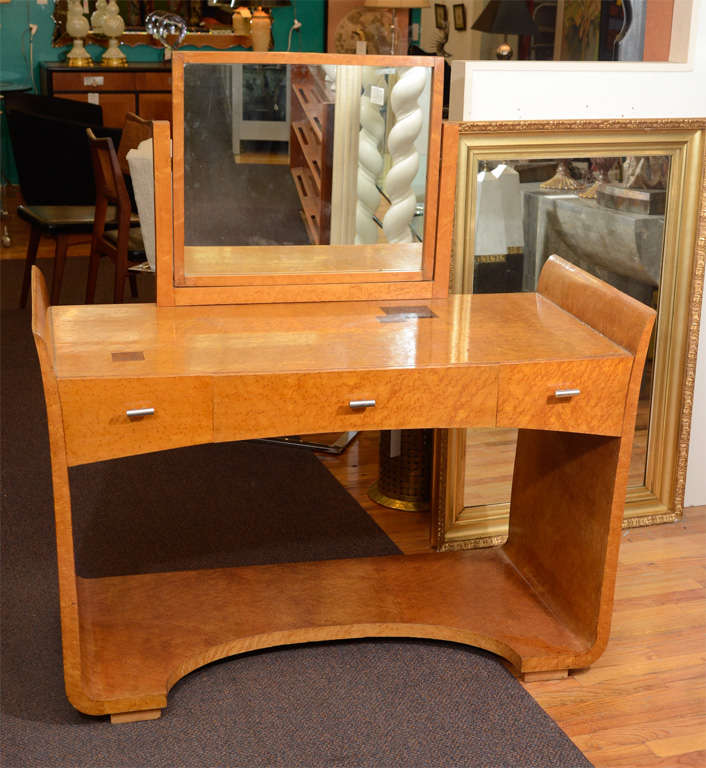 A vintage Art Deco vanity table in bird's-eye maple with inlaid geometric details. The mirror pivots (the reverse is bird's-eye maple) and there are three drawers with chrome pulls by Eugene Schoen.
 