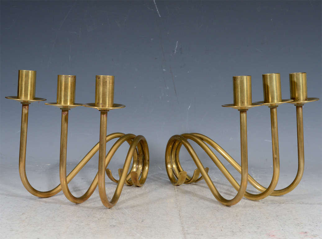 A pair of vintage brass candlesticks or candelabra, each designed as a curving 
