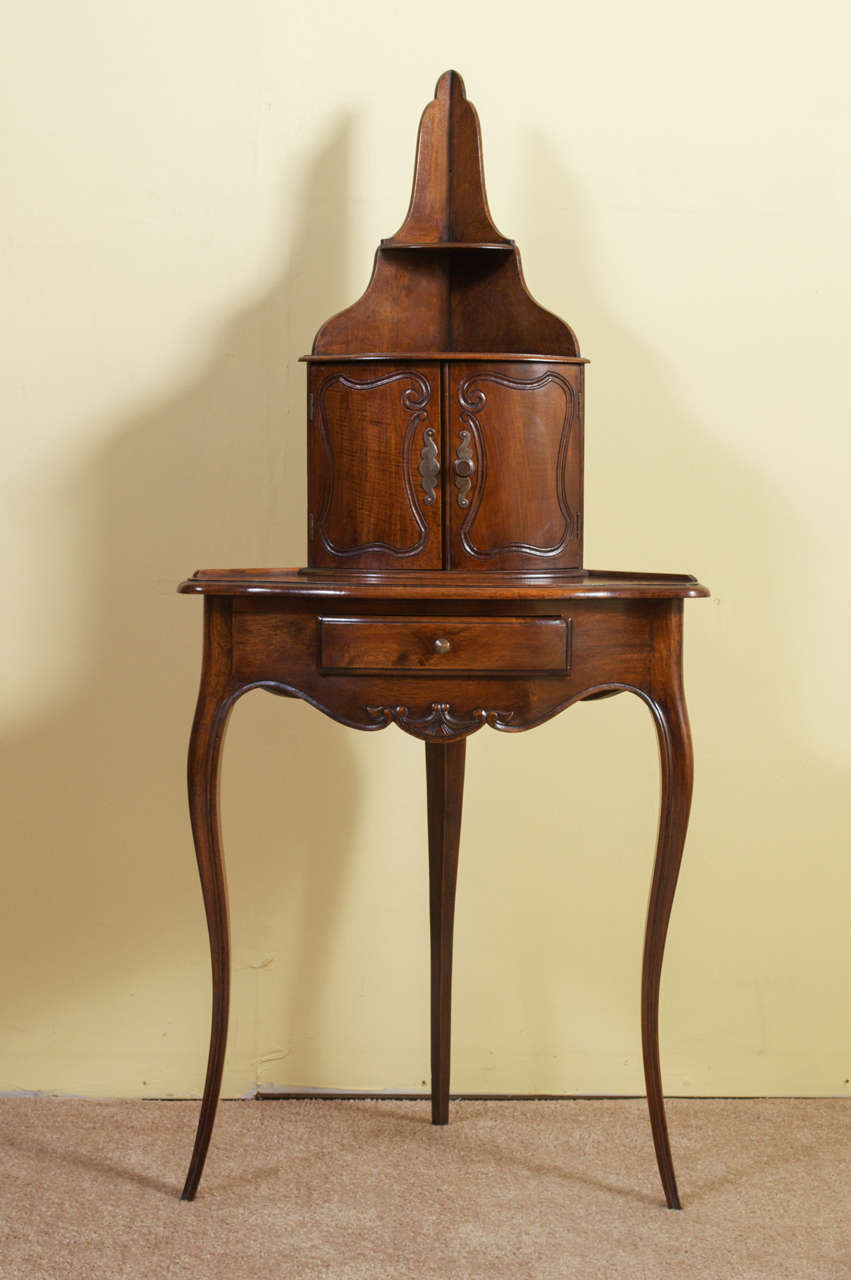 A gorgeous Louis XV Style Walnut Corner Stand. The upper part of the Stand has two shelves above two doors. The lower part has a drawer above a carved scalloped apron that leads to cabriole legs. This corner piece has a beautiful, rich color and a