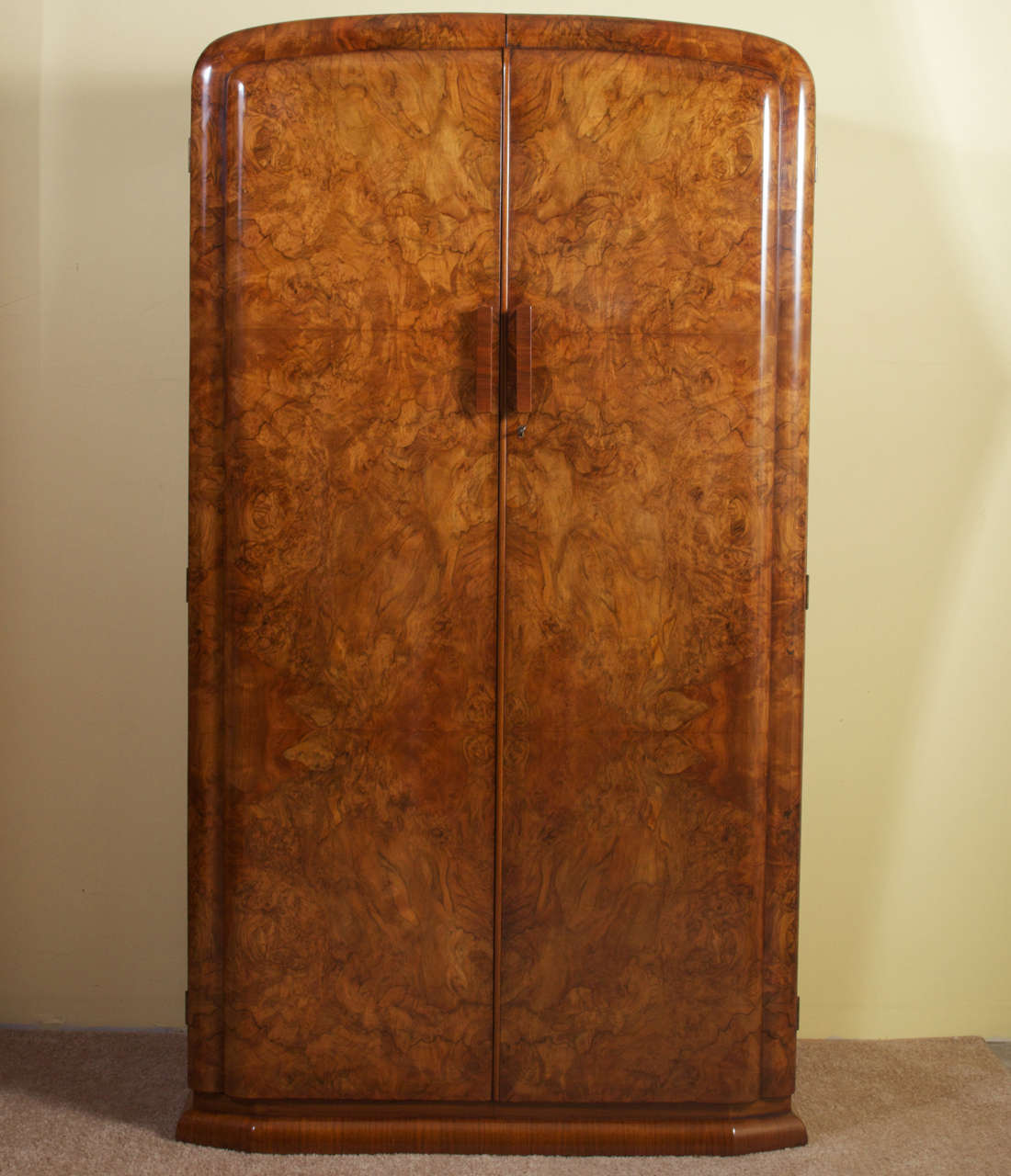 A unique Art Deco burl walnut two-door wardrobe with fitted interior. There is a beautiful symmetrical veneer pattern on the front, as well as the back, of the doors. Below the deep top shelf of the interior there is a pull-out closet pole on the