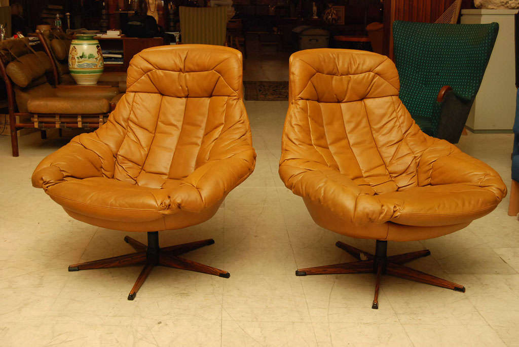 Pair of swivel armchairs upholstered in soft brown leather on a cinque-ped metal base painted to resemble rosewood.  Great loungers