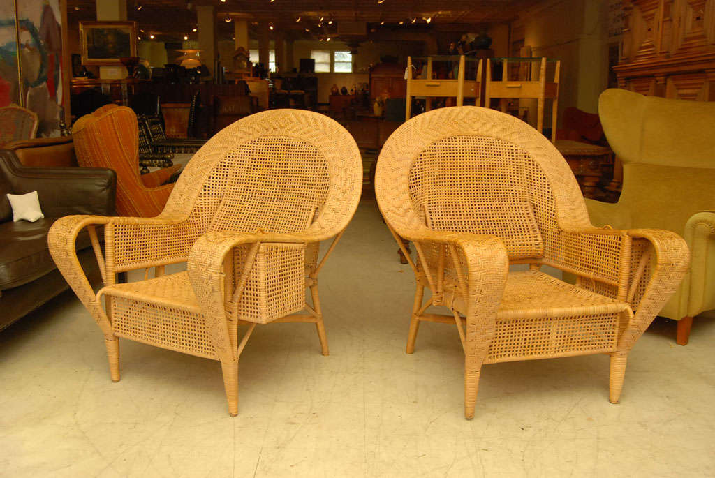Large pair of wicker armchairs by Danish designer Kai Fisker, complete with glass holder on one side and compartment for sunglasses, book, etc., on the other