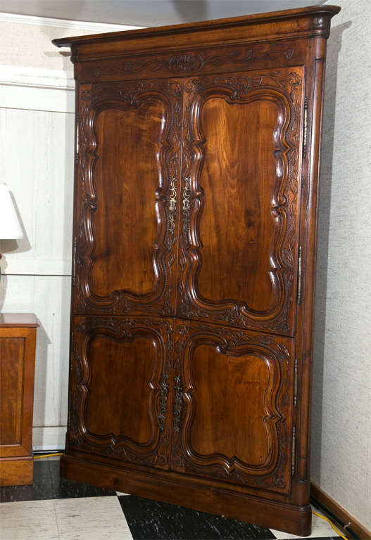 French cherry corner cupboard with asymmetric doors have exquisite foliate relief carving and the raised panels are outlined in a lacy carving as well. Inside, we find nicely spaced shelves two in the upper section and a single shelf down below.