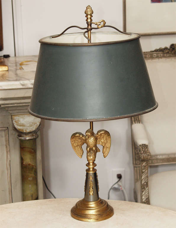 Bronze French Empire style lamp with dark green tole-peinte shade, circa 1930, France. The tapering decorated standard is summounted by an eagle and sits atop a circular base. The shade, housing two bulbs, is adjustable using the bronze key at top.