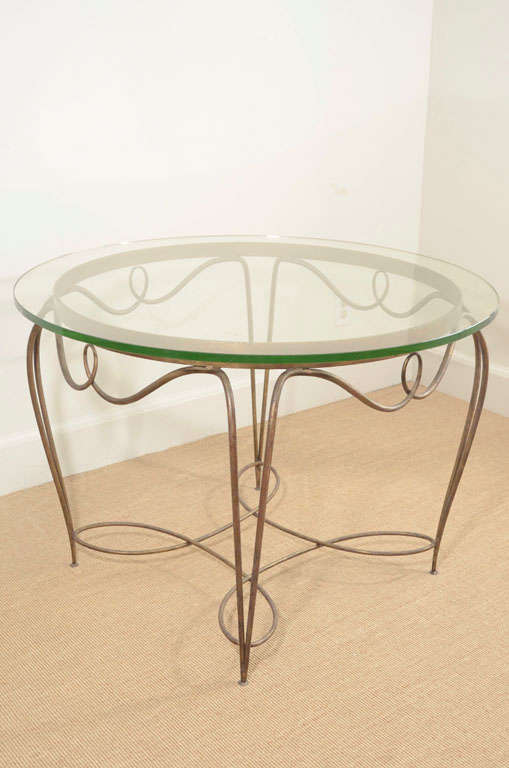 The gilt hand curved wrought iron fame supporting a circular glass top.