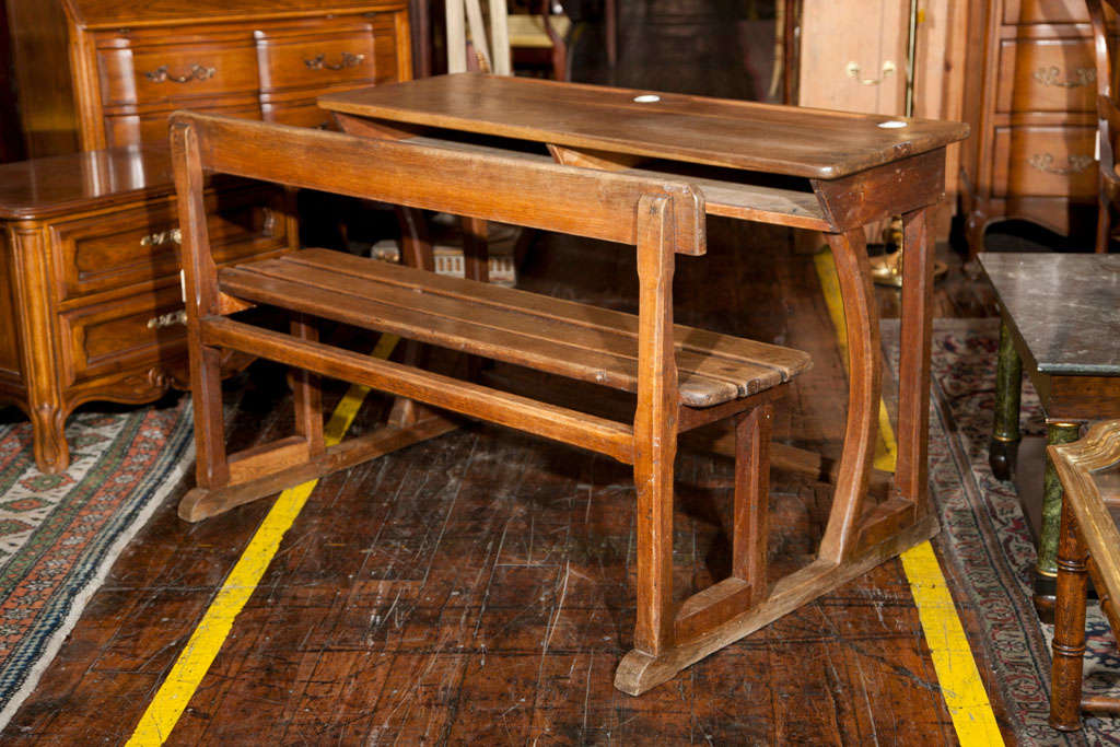 Oak double school house desk with slat bench, porcelain inkwells and pencil slots.