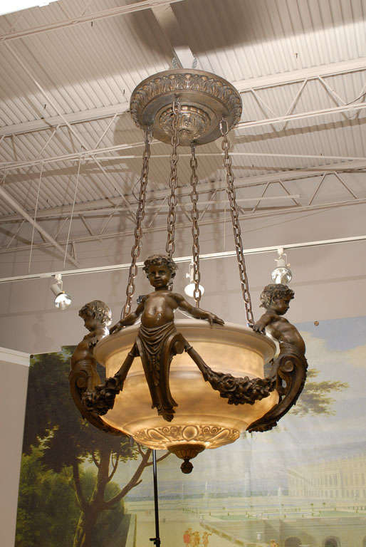 Large decorative faux alabaster and faux bronze plafonnier featuring cherubs and garlands supported by four bronze chains, has six internal lights.