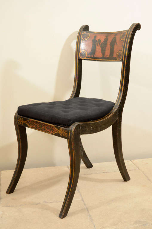 A pair of English Regency painted and gilded side chairs in the Etruscan taste with sabre legs, caned seats and handstitched tufted shaped cushions