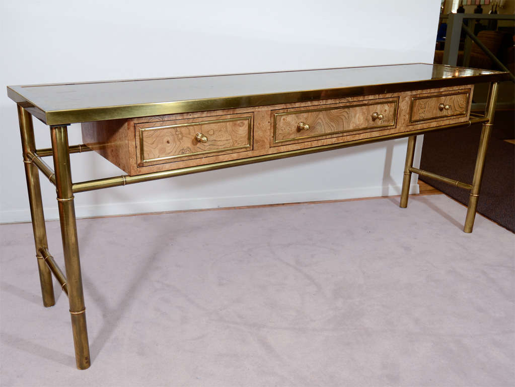 A long console table by Mastercraft in light tone amboyna burl wood and textured brass. The piece has three drawers, each with brass pulls and detailing.<br />
<br />
Reduced From: $5,800