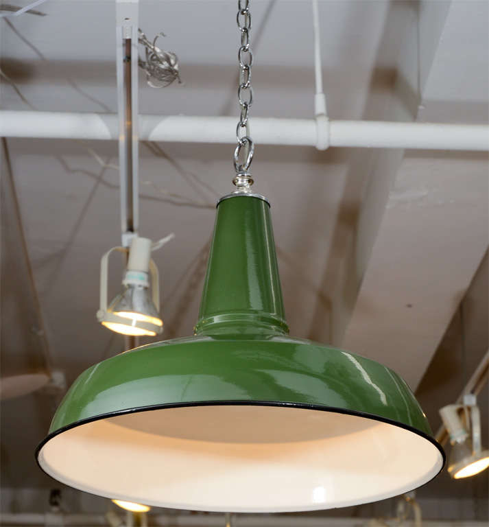 A pair of mid century industrial hanging lights composed of a metal shades with white interiors and deep green exteriors. The rim of each shade is black and the cap and hanging ring of each is chrome. Each has been newly re-wired.

Reduced From:
