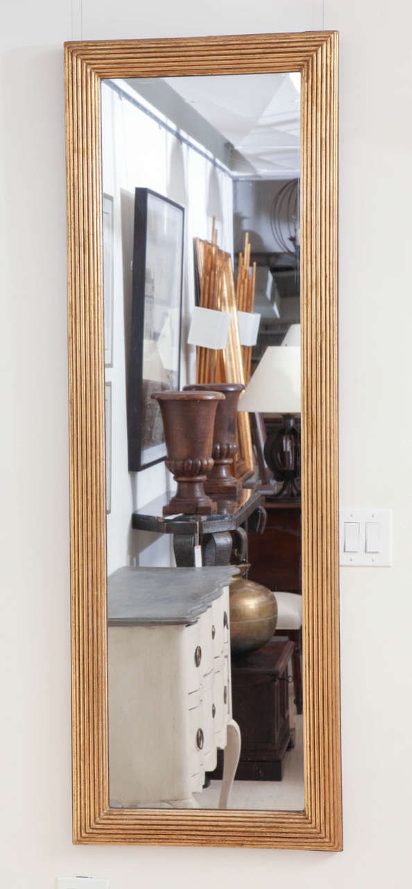 Tall, narrow ribbed gilt wood mirror with semi-circular ribbed frame