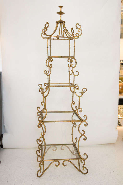 This amazing Italian pagoda shaped four tier etagere is gold leafed and constructed of wrought iron.  Featuring a stylized finial and beautiful scroll detail with four glass shelves.  Glass shelves are removable and the piece   breaks down to two