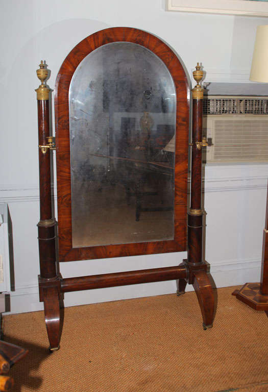 Very fine French Empire cheval mirror in highly figured mahogany and with chased gilt bronze mounts, the arched mirror suspended between two columns standing on arched tapering square feet, the whole mounted in fire gilt bronze mounts and retaining