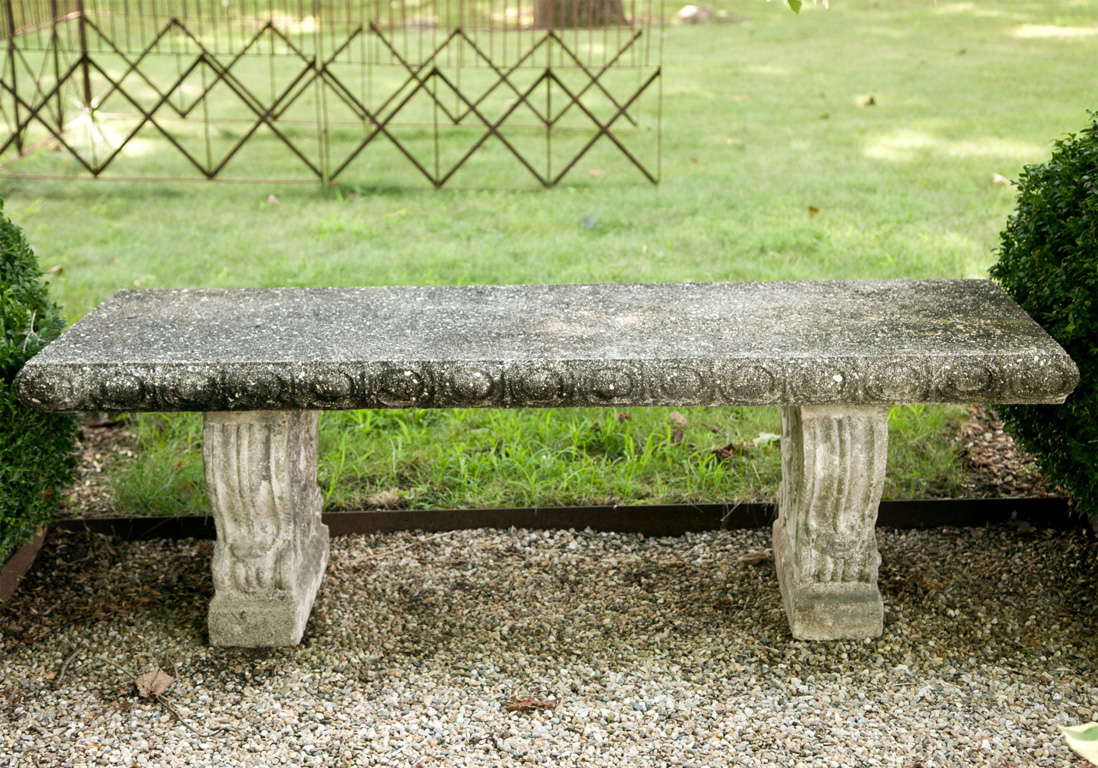 This heavy and exceptionally well-made cast stone garden bench features classical elements, including egg and dart rim and volute decoration to the supports. Larger in size and much more stately than the average garden seat, and with its