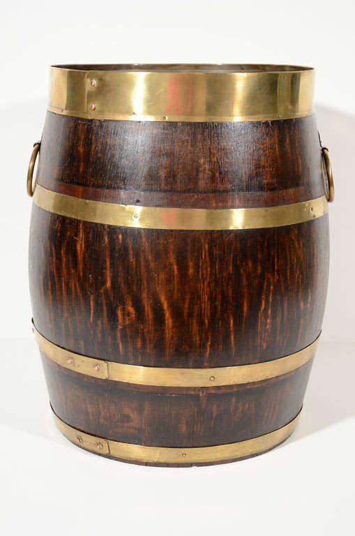 A handsome English oak barrel with brass banding and ring handles, ideal for firewood or newspapers.