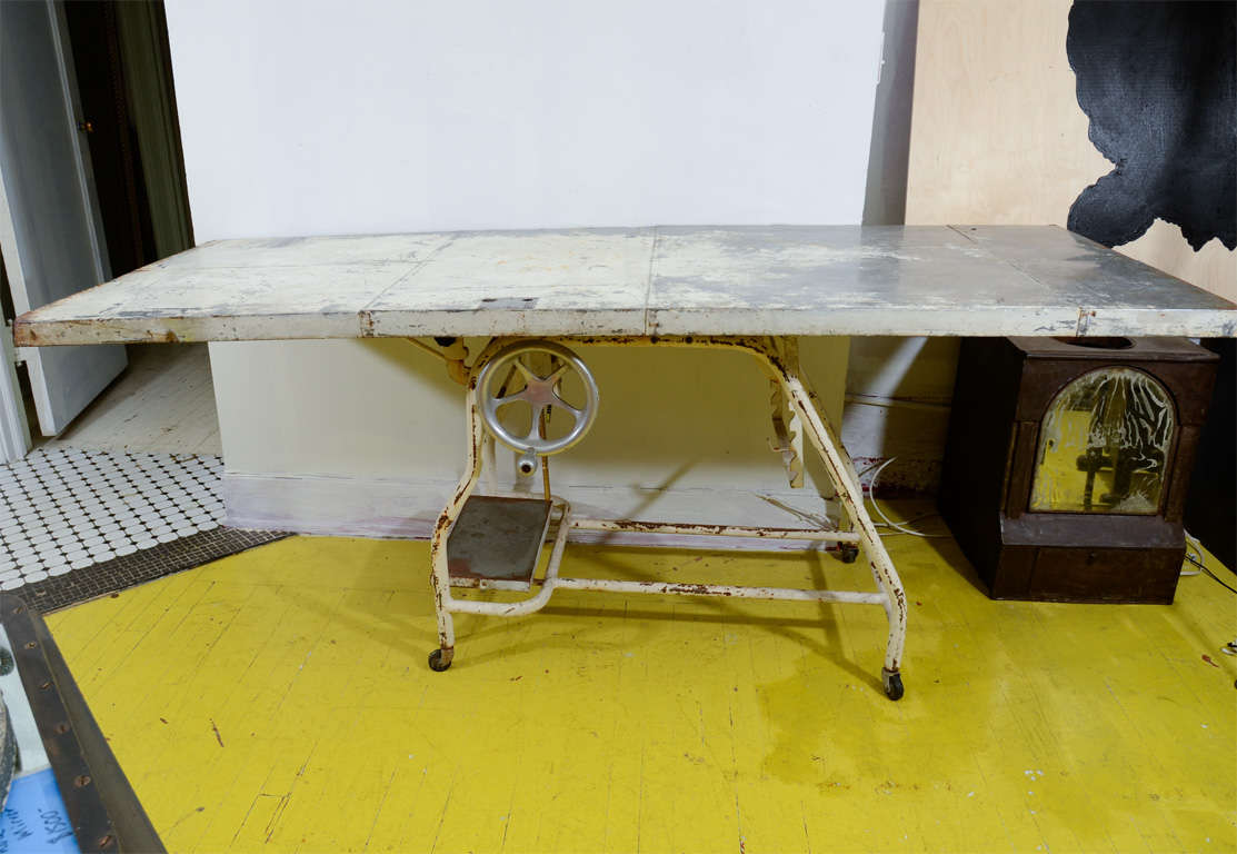 White painted metal table with crank and on casters.