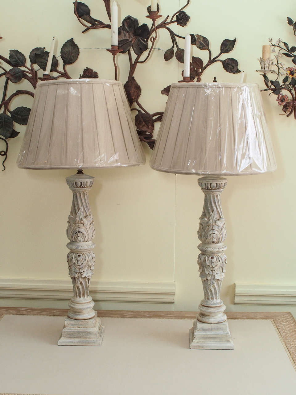 Great looking pair of highly carved painted wooden lamps made from sections of vintage bed posts.  The standards, decorated with acanthus leaves, fluted swirls, and  egg and dart pattern, are raised on a stepped plinth base.  Shades are included. 