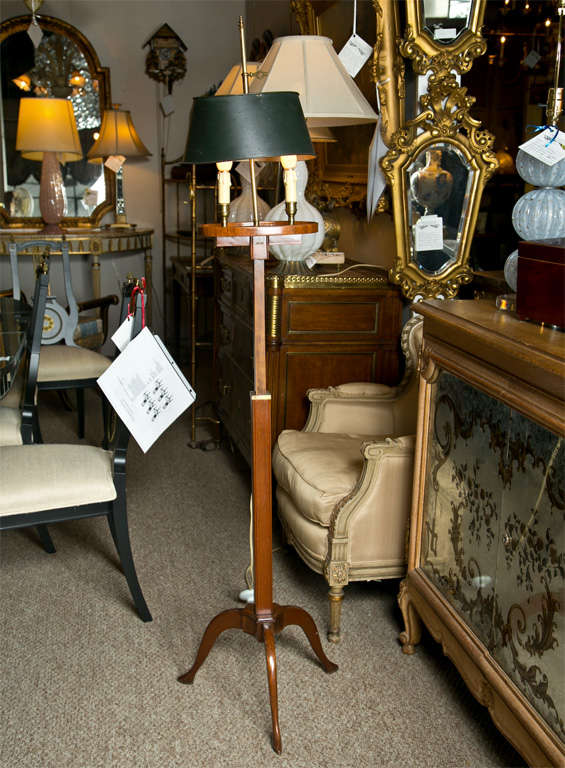 A handsome and original mahogany bouillotte floor lamp stamped Jansen, two-arms, tole shade, standing on a tripod base.