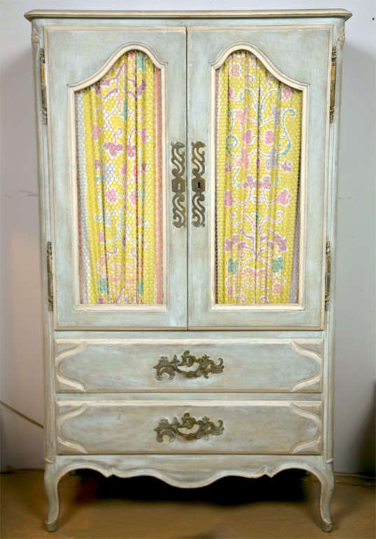 Shabby chic style distress-painted armoire, 20th century, the cabinet top with wired door and fabric backdrop opens to shelving interior atop two drawers, raised on cabriole legs.