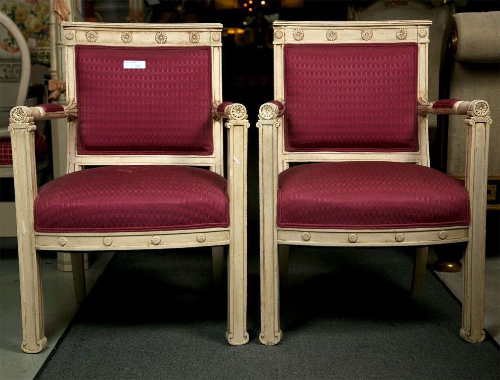Pair of French Empire style painted armchairs, slightly distressed frame, square back with florette-decorated molding, padded back and seat, straight and back-swept legs.