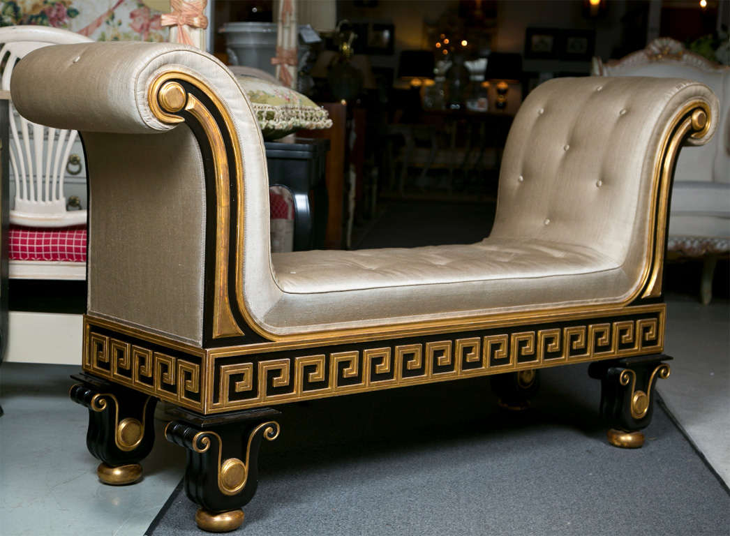 Attractive custom-made ebonized and parcel-gilt bench with rolled arms, circa 1970s, upholstered and tufted in silk, elegant Greek key carving on the apron, raised on four urn form decorated legs.