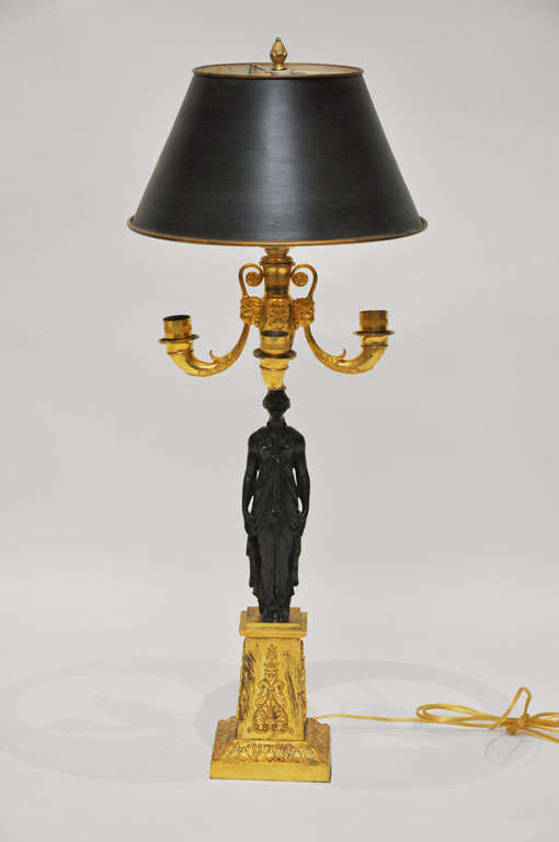 French 4-light patinated and gilt bronze bronze candelabra converted to a lamp. The patinated bronze supporting pillar in the shape of a barefoot Grecian caryatid with draped tunic and flowing hair upswept in a bun; supporting on her head a gilt