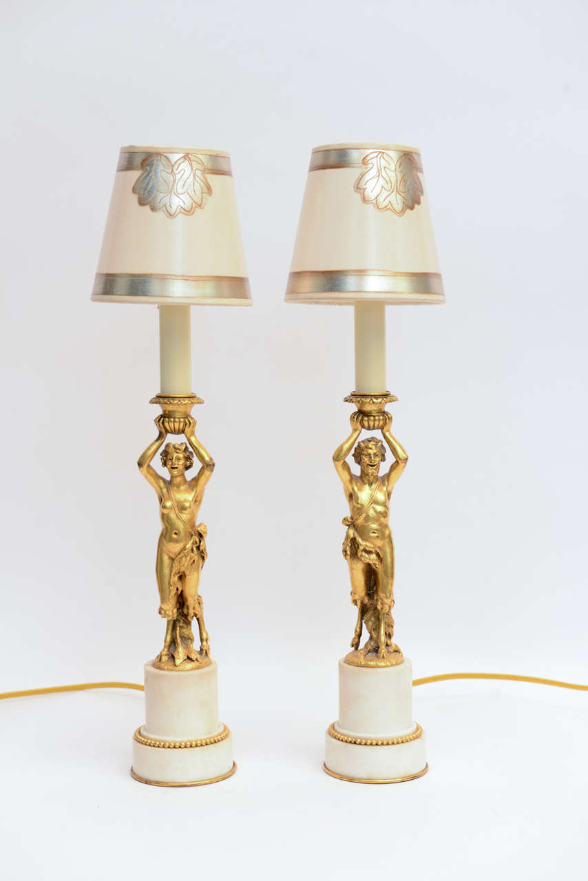 A pair of gilt bronze female and male candlestick on marble pedestals by Caldwell.