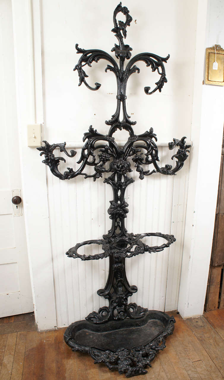 19th century black painted cast iron hall stand with hooks for
hats or coats and loops for umbrellas with drip pan.