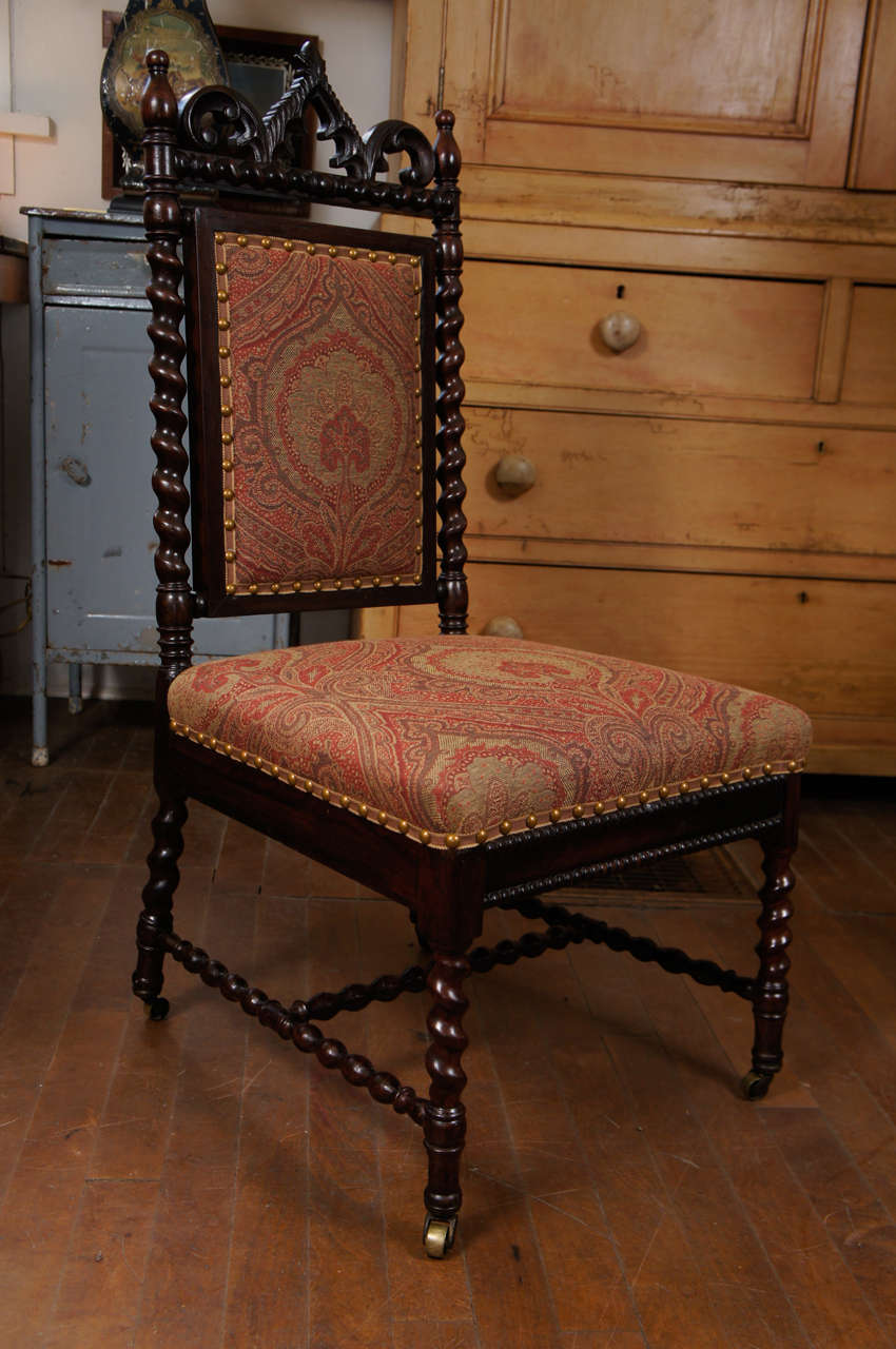 Really enchanting Gothic Revival walnut side chair with turned wood side rails,
and legs, carved crest. On casters. Paisley upholstery, gimp and brass nailhead detail give chair charming finished look.