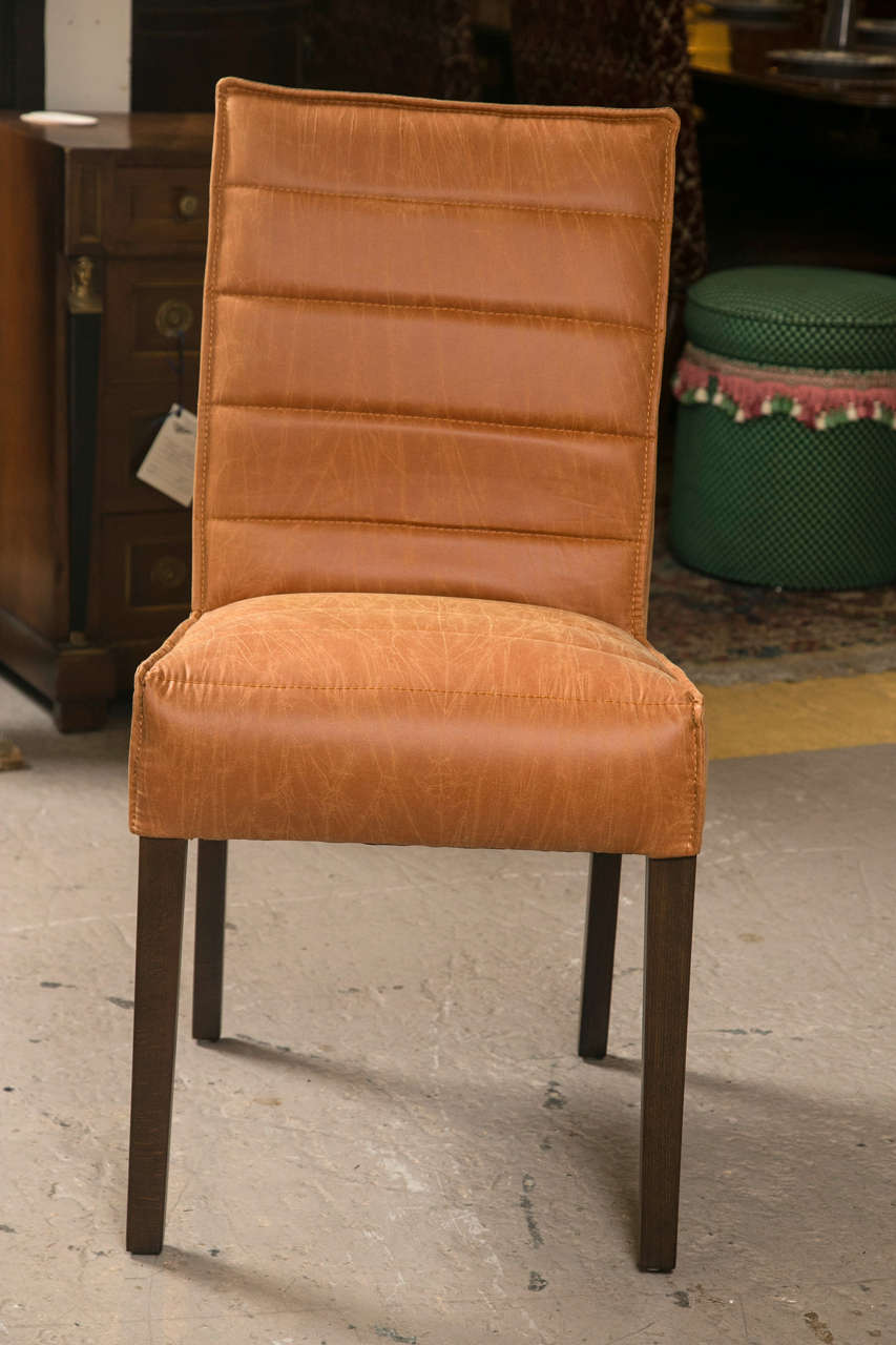 Pair of Hollywood Regency style leather side chairs. Each with a set of mahogany tapering legs supporting a finely padded seat with stitching. The matching backrest having a chrome handle to lift and move.