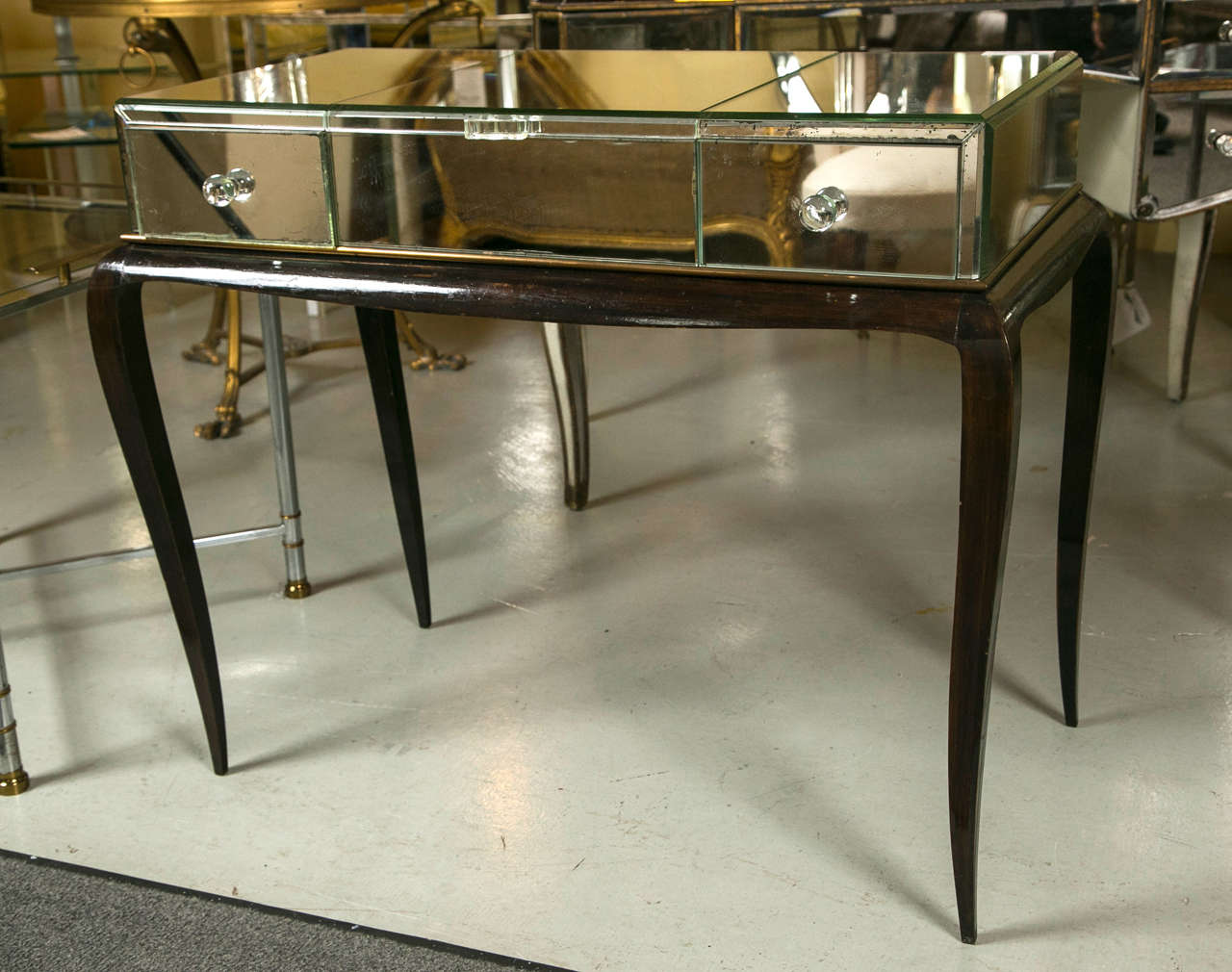 A fine Art Deco mirror and ebonized flip-top ladies desk on curved wooden legs. This vintage mirrored desk top is supported by curved legs which hold a bevelled mirror glass flip-top vanity flanked by side drawers.
Top measurements: 32.75 width by