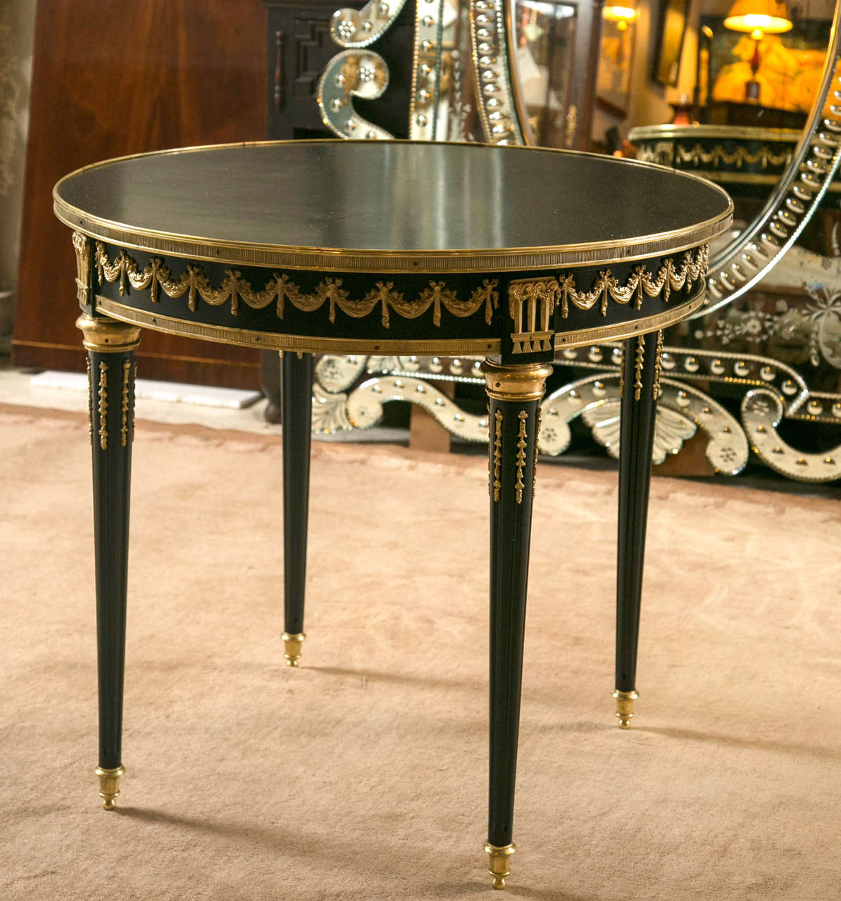Ebonized and bronze mounted centre table by Maison Jansen. This fine Louis XVI style centre table has bronze chased sabots leading to tapering fluted legs terminating in bronze flames and bronze caps. The bronze framed apron having ribbon and swag