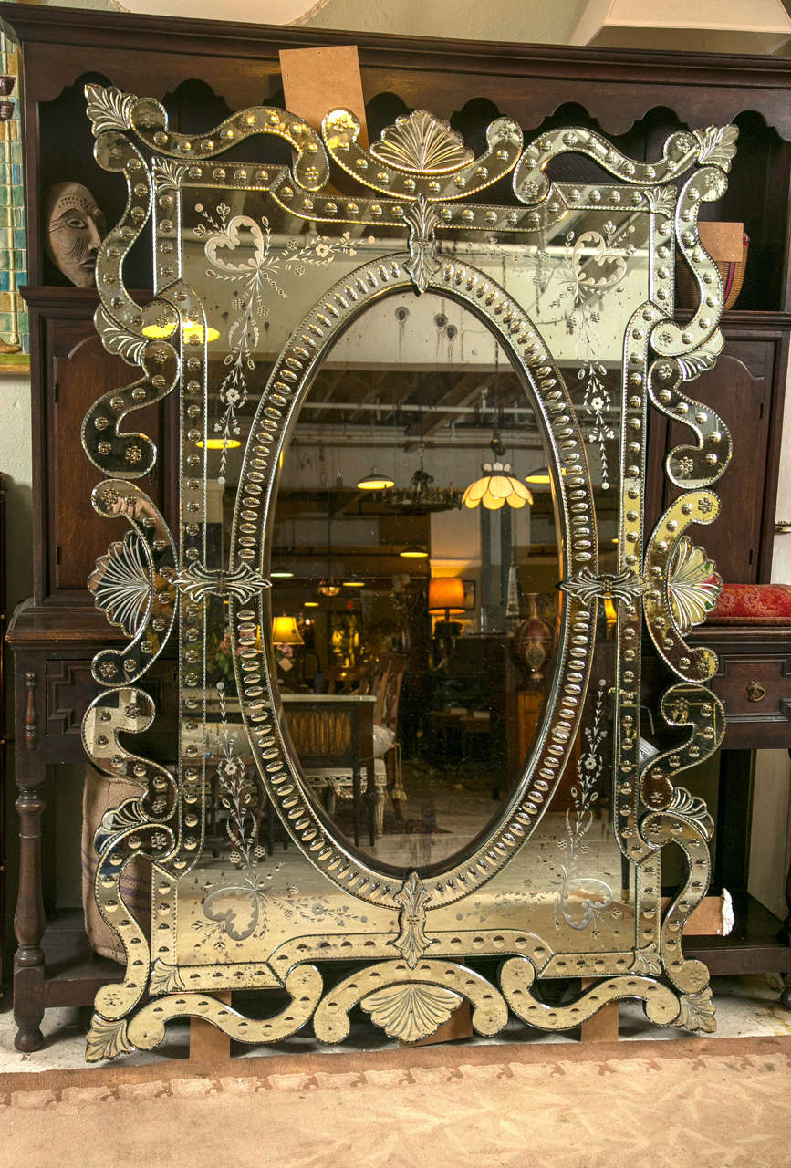Pair of monumental Venetian mirrors. The oval center beveled mirror framed in an etched mirror glass setting. Swags and floral design too numerous to name. This palatial mirror will make a Fine statement in any setting.