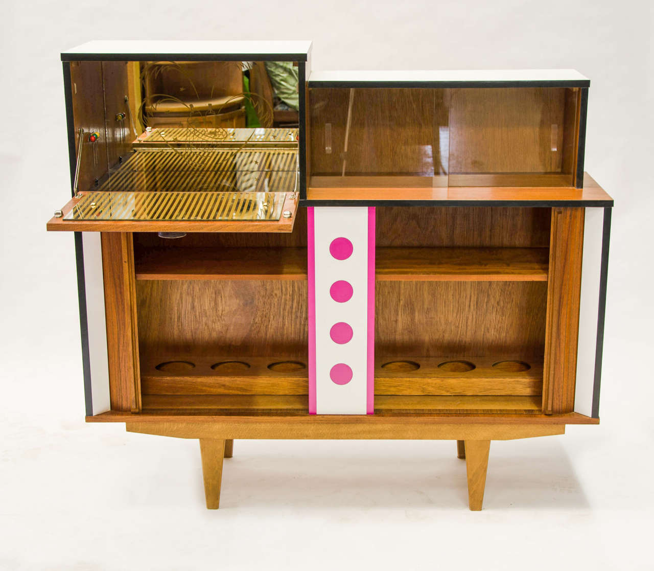 A teak and laminate veneer drinks cabinet featuring bottle storage rack, fold down mirrored drinks shelf with period graphics. New color laminates applied for further accentuation of the design.
