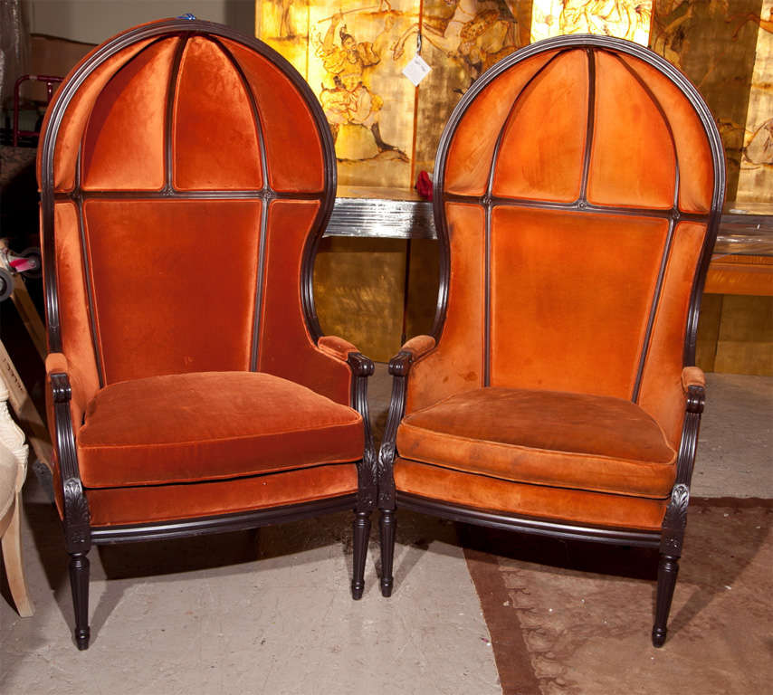 A fine pair of Hollywood Regency style porter's chairs, stained wood frame upholstered in dark orange fabric, hooded back, raised on fluted tapering legs.
