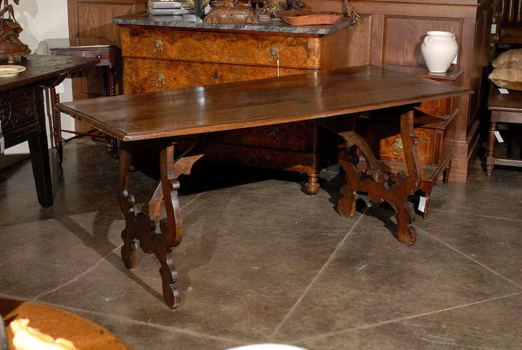 An early 19th century Italian walnut table. This Italian table from circa 1800 features a rectangular top over two lyre shaped legs. A unique looking stretcher, reminiscent of tree branches, connects the lower portion of the lyre legs to the center
