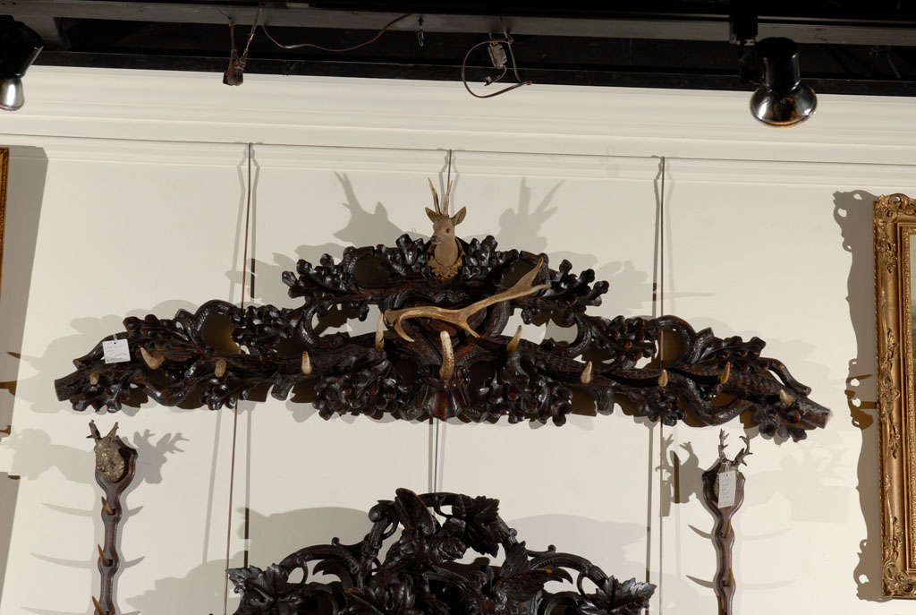 A German Black Forest large size coat rack from the early 20th century. This wall-mounted coat and hat rack from the 1900s features a richly carved wall decoration with a central deer head. Below the deer head sits a large horizontal branch