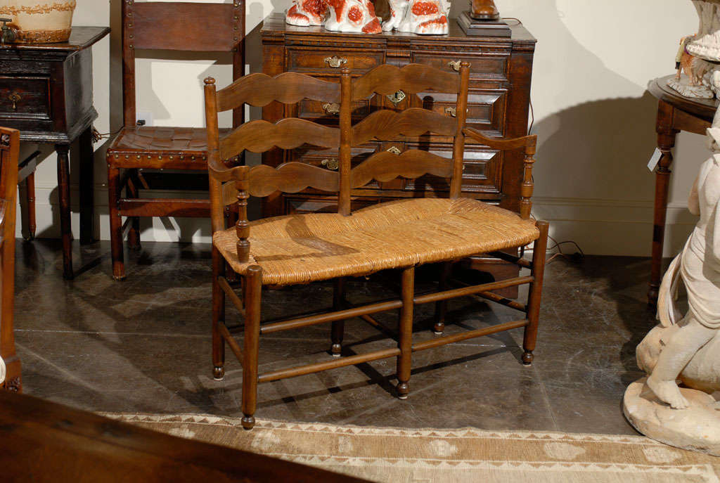French rush seat bench with curved arms and scallop back.
