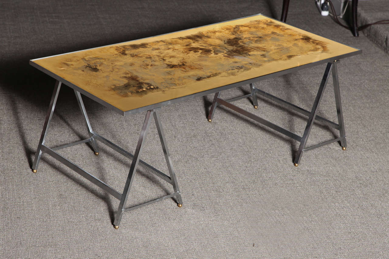 Trestle base coffee table in brushed steel with églomisé top in gold, grey and black.
