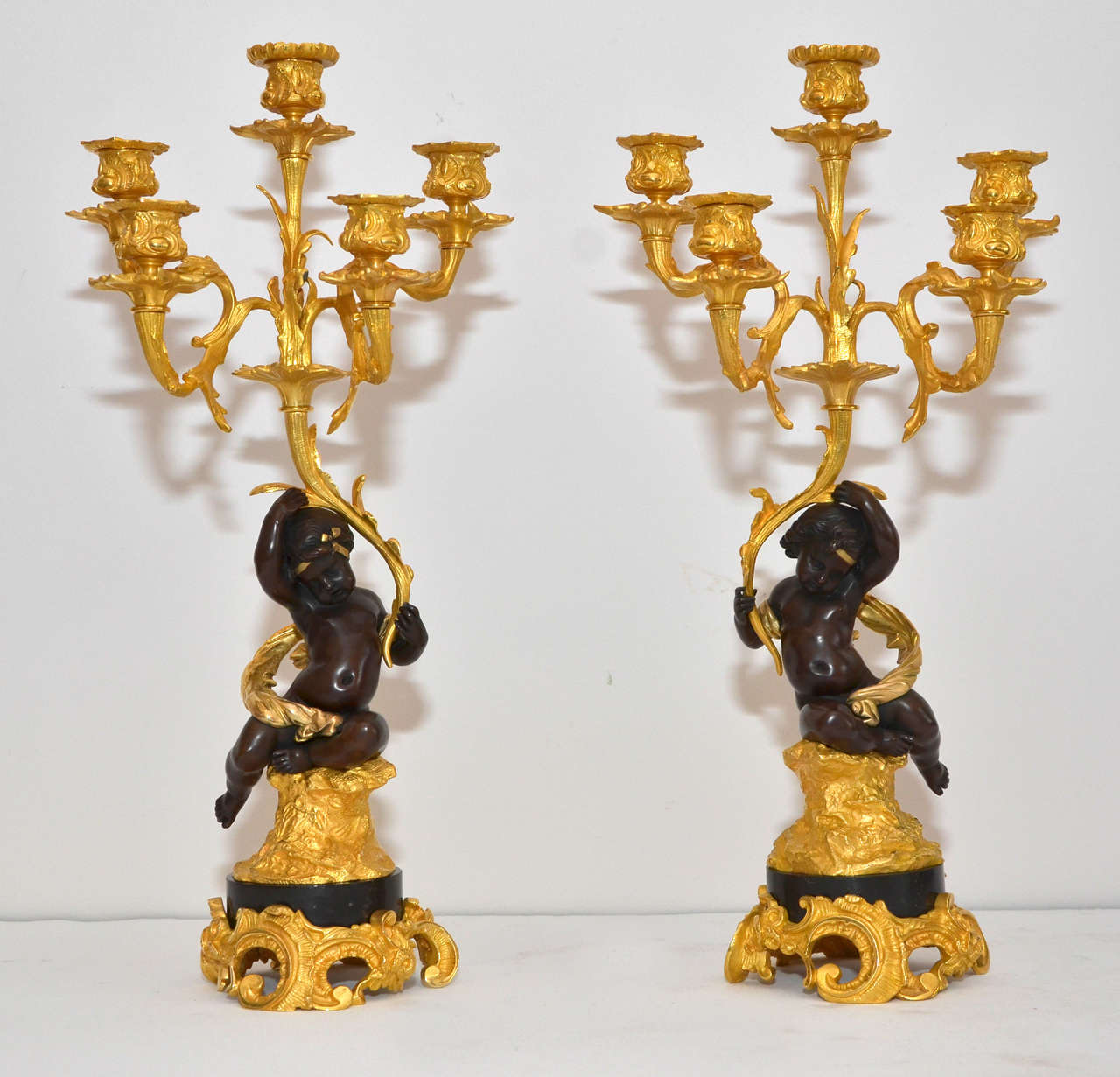 pair of double patina bronze candelabras, representing putti holding  5 arms of candelsticks.