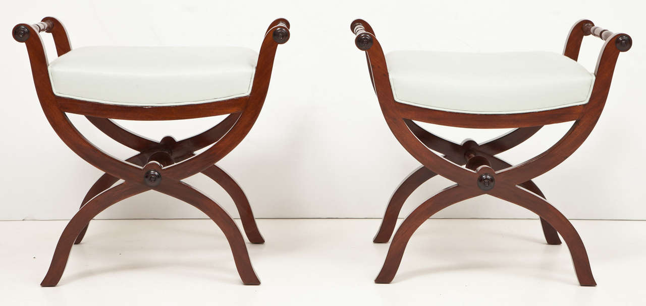 A pair of Swedish Empire stools, circa 1820-1830, each with upholstered seats and curule form frame joined by turned stretchers.