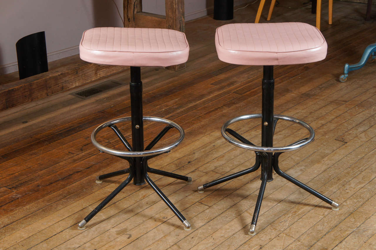 Pair of pink, black and chrome vintage stools. Swivel pink vinyl seats with chrome footrest and feet.