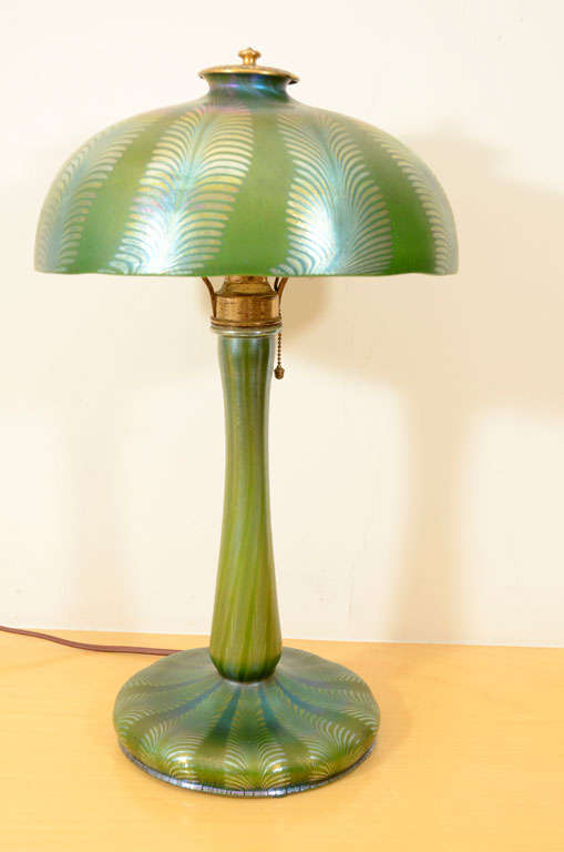Beautiful and and unusual Tiffany favrile iridescent glass lamp, matching shade and base, shade engraved L.C.T favrile, base engraved L.C.T. Tiffany favrile. Iridescent gold design on green iridescent glass. The diam. of shade is 10