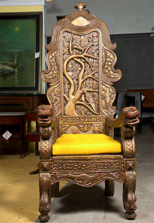 An ornately carved Chinese Throne Chair. The clay and gilt decorated arm chair depicting a bird perched upon the tree of life complete with carved dog head arms.