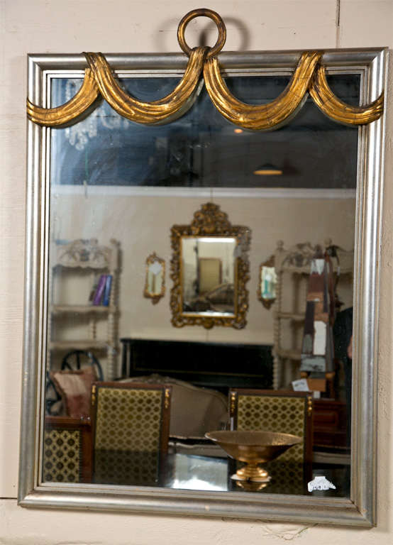 Mid-century silver-gilt mirror in the style of Dorothy Draper, the top decorated with gold-gilt drapery and a loop.
