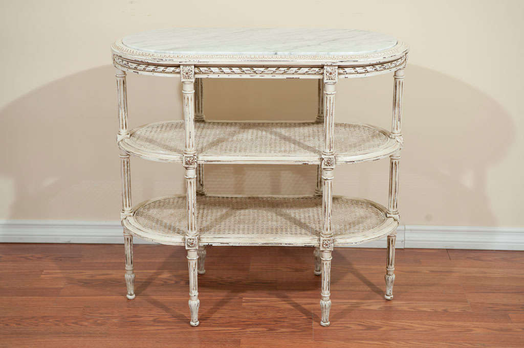 Louis XVI style three tiers painted side table has a marble top and two lower caned shelves.