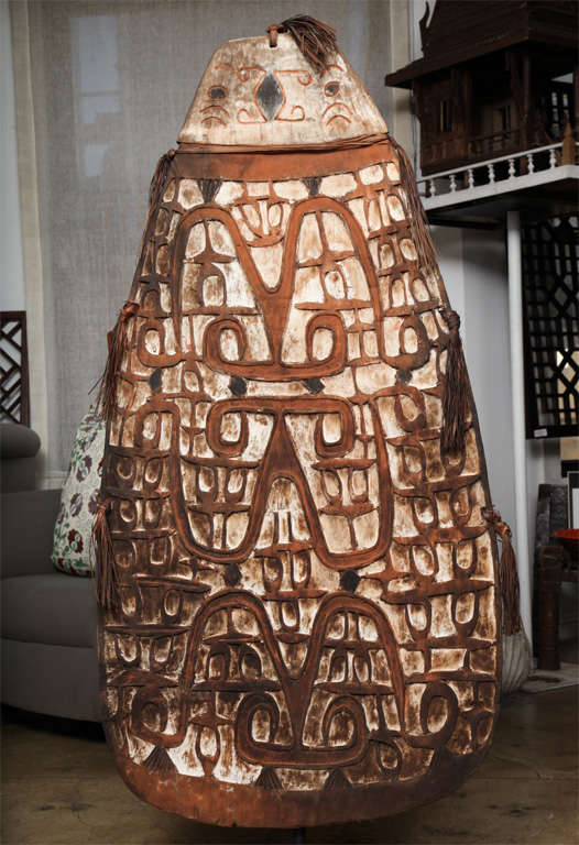 An Asmat War Shield from Irian Jaya in Papua New Guinea.  This hand carved artifact has retained its bold carved patterns in relief as well as its original pigments.  Mounted on a metal stand.