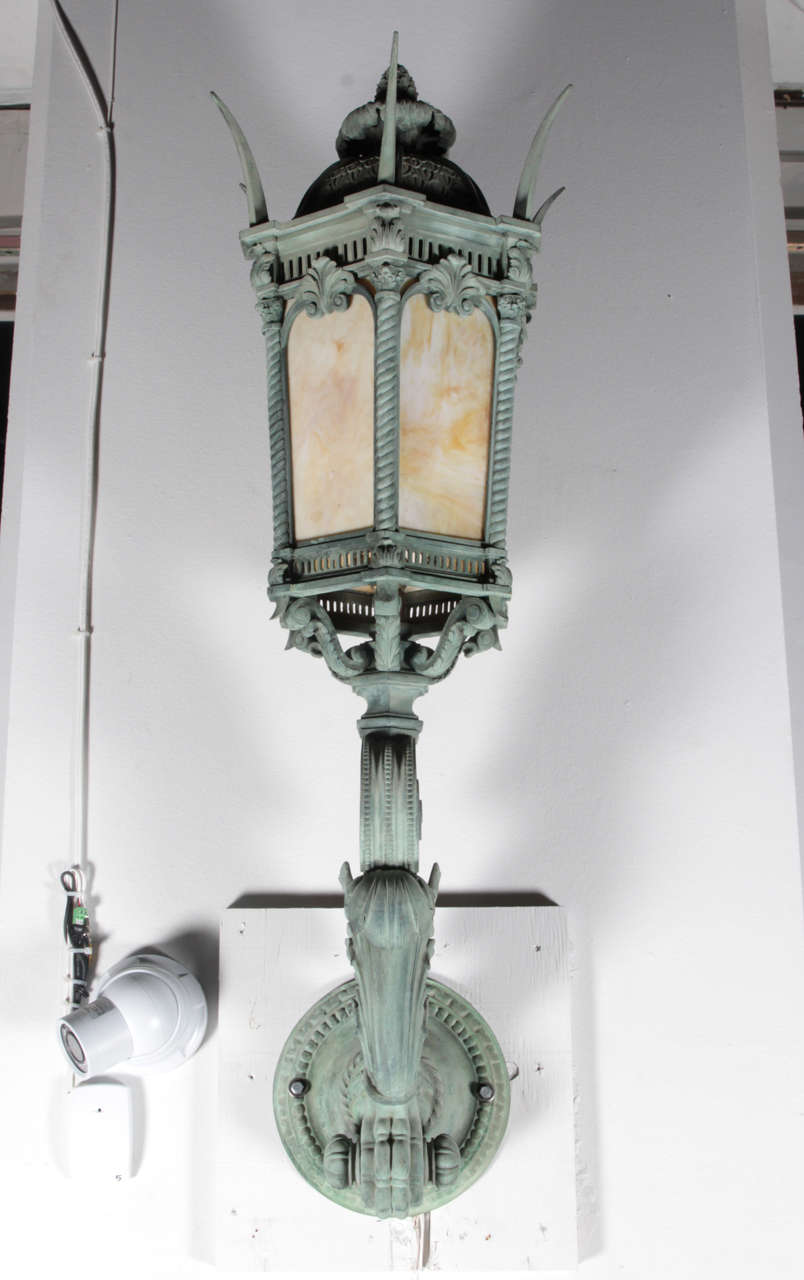 These unique exterior sconces have original verdigris patina.  Acanthus leaf and claw detail with excellent castings throughout.  Original amber slag glass. These sconces are in all original condition with no repairs - Museum quality.