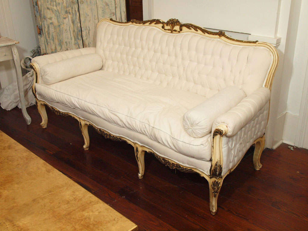 Gorgeous antique Italian tufted large settee with painted and gilded frame.   It features beautiful Louis XV hand-carvings and is solid wood. Flowing lines, cabriole legs and original patina, make this one of a kind piece a work of art.  Upholstered